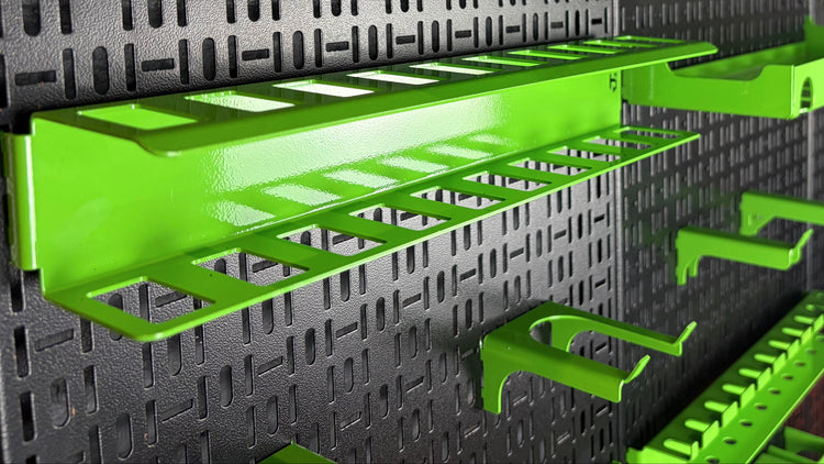 Green wall-mounted storage shelves on a black pegboard