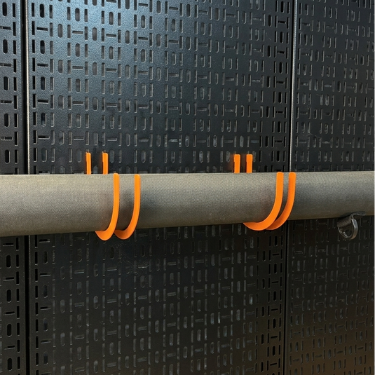 Orange hooks attached to a gray rod against a black textured wall.