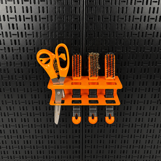 Orange tool holder with various tools on a black pegboard
