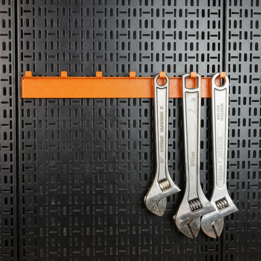 Three adjustable wrenches hanging on an orange magnetic strip against a black textured wall.