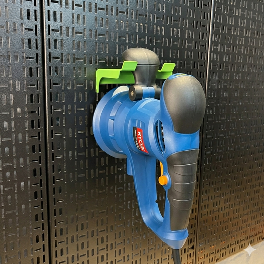 Blue and gray power tool with green accents on a pegboard wall.
